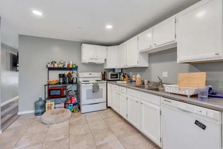 Kitchen featuring white cabinetry, a built-in dishwasher, tile flooring, and recessed lighting