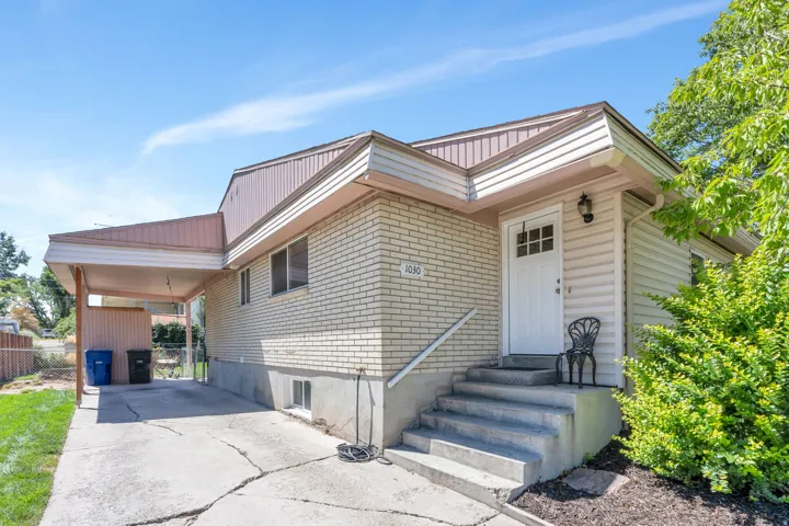 Brick and siding exterior with a covered carport, front entry with transom window, and concrete front steps