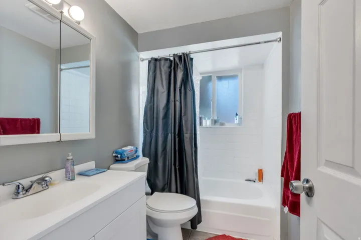 White vanity with an integrated sink, polished chrome faucet, and mirrored medicine cabinet