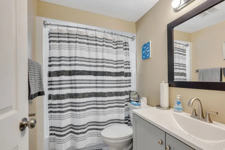 Vanity with integrated sink, brushed nickel faucet, wall-mounted mirror, and overhead light fixture