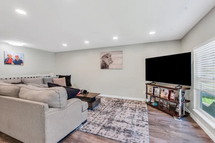Recessed lighting, wood-finish flooring, and a large window with blinds