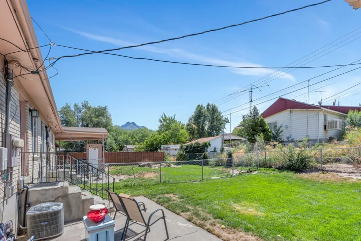 Spacious backyard with mature landscaping, lush lawn, and established trees framing the property