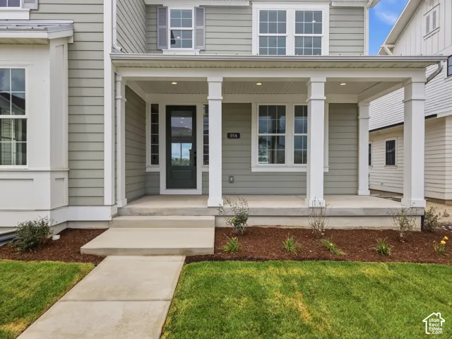 Covered front porch with white columns, light green siding, and a dark entry door with glass