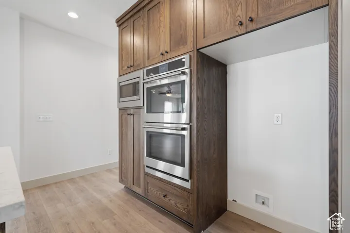 Built-in stainless steel microwave, double ovens, and integrated refrigerator space complement the wood-finish cabinetry and wood-finish flooring