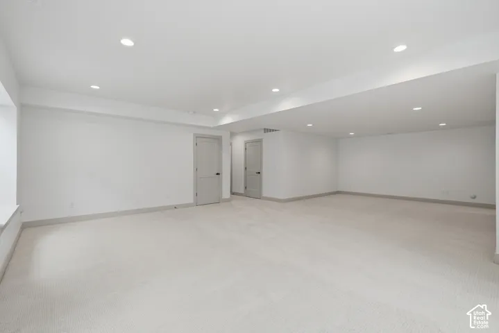 Expansive room featuring recessed lighting, light-toned carpeting, two interior doors, and a window with a deep sill