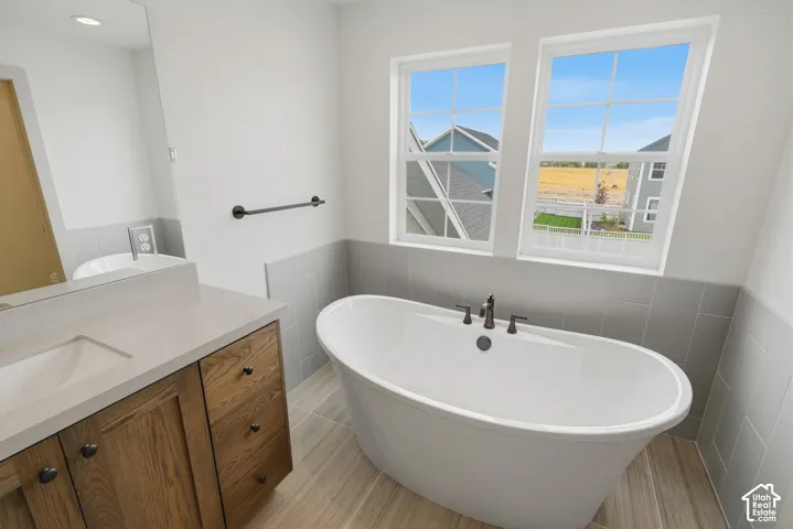 Primary Suite. Freestanding oval soaking tub with dark-finish fixtures, dual windows, and wood-finish flooring