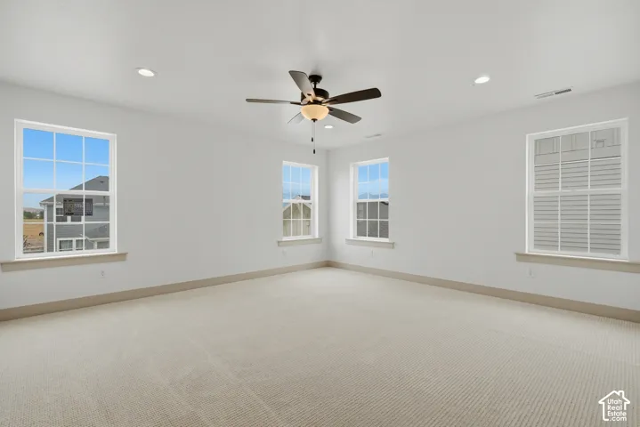 Primary Suite. Spacious room featuring carpeting, multiple windows, recessed lighting, and a ceiling fan