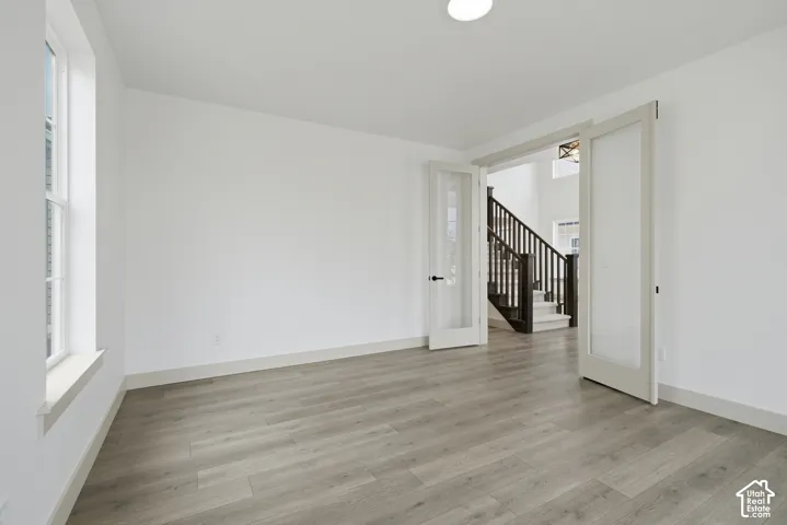 Spacious room with wood-finish flooring, white walls, and a large window
