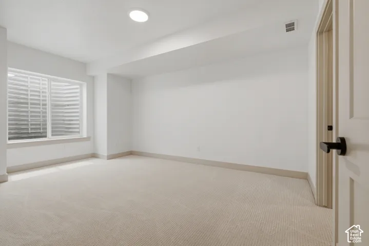 Recessed ceiling lighting, light-toned carpeting, white walls, and a window with blinds