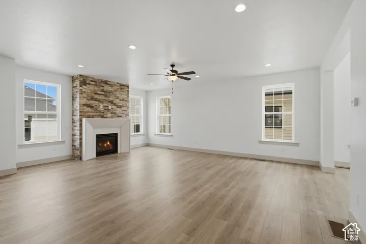 Spacious interior featuring wood-finish flooring, a stone-clad fireplace with a white mantel, recessed lighting, and multiple windows