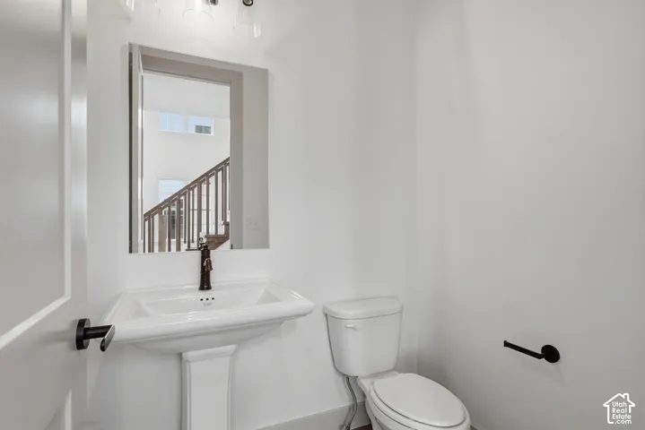 Pedestal sink with bronze-finish faucet, rectangular mirror, and overhead vanity lighting