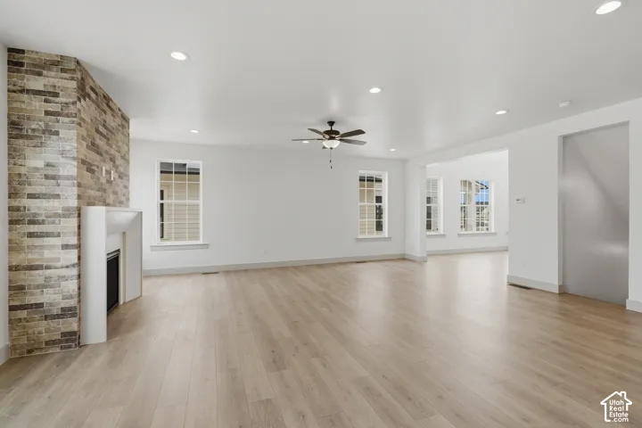 Wood-finish flooring, recessed lighting, and a stone-accented fireplace with a white mantel