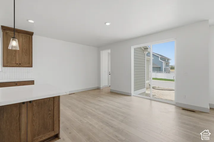 Light wood-finish flooring, white walls, recessed ceiling lighting, and a sliding glass door