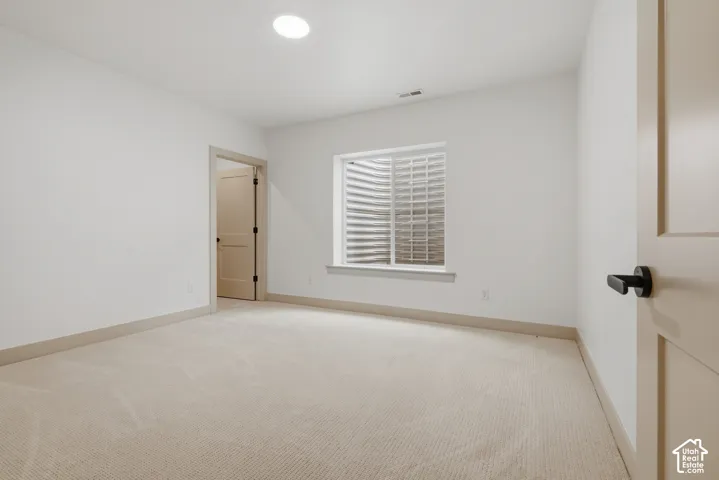 Recessed ceiling lighting, white walls, light-toned carpet, white window trim, and white paneled doors with black hardware