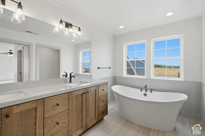 Primary Suite. Dual sink vanity with wood-finish cabinetry, white countertop, and matte black fixtures