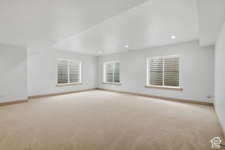 Recessed lighting illuminates the expansive carpeted floor and three egress windows