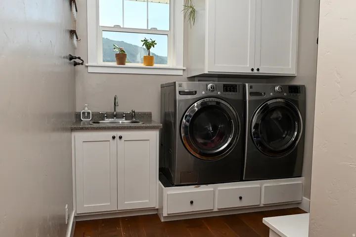 Laundry area featuring a utility sink with a built-in cabinet, overhead cabinetry, and a hardwood-style floor