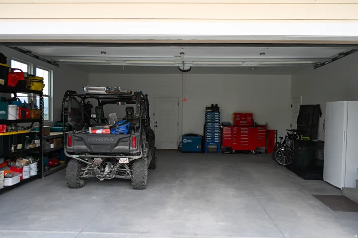 Attached two-car garage with a concrete floor, white walls, and a window for natural light