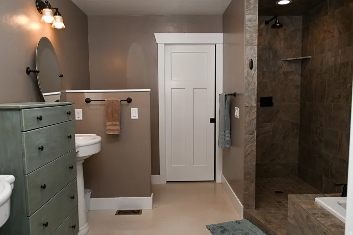 Pedestal sink with an oval mirror and wall-mounted lighting