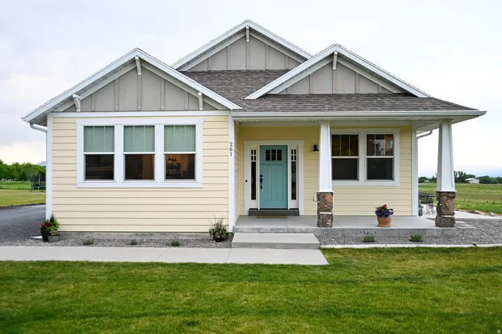 Light yellow siding exterior with a turquoise front door, covered porch, and white trim