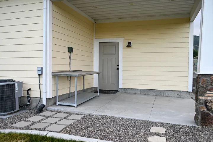 Concrete patio with gravel and paver accents, durable siding, and stone column detailing