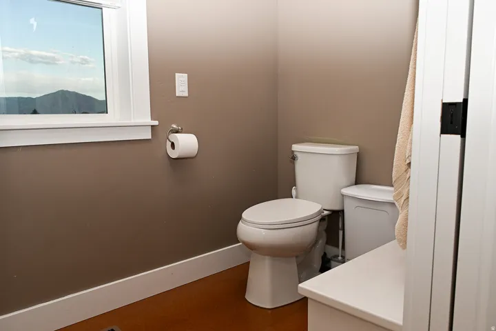 Toilet with a window, white trim, and neutral-toned walls