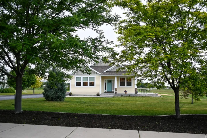 Single-story residence featuring light yellow siding, a light blue entry door, and a covered porch