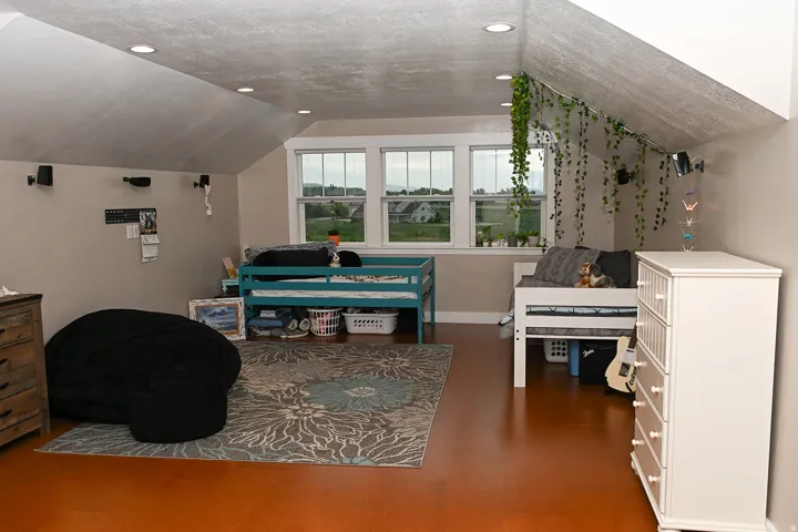 Attic space featuring sloped ceilings, recessed lighting, and a three-panel window