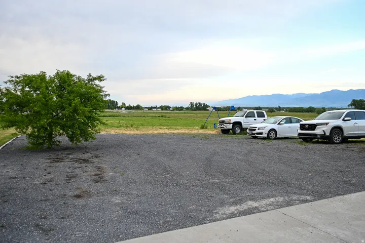 Expansive gravel lot with mature tree and distant mountain backdrop