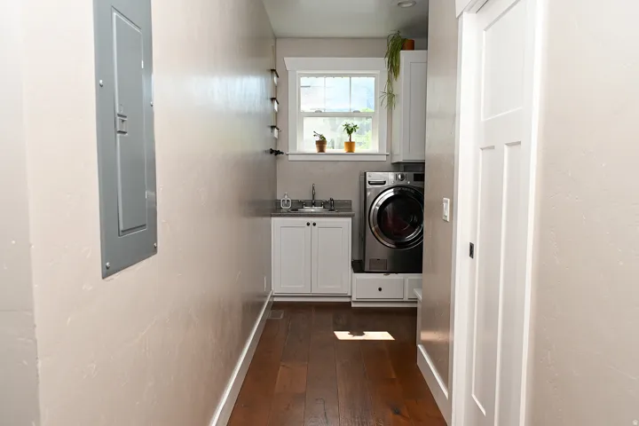 Front-loading washer and dryer, built-in cabinetry, under-mount sink, and dark wood-finish flooring