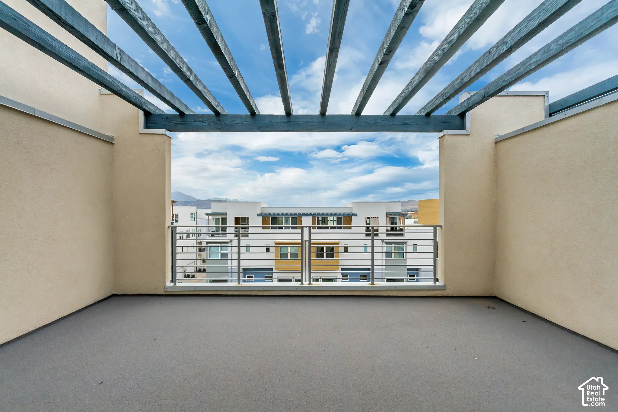 Rooftop deck featuring a slatted pergola, stucco walls, and a metal railing