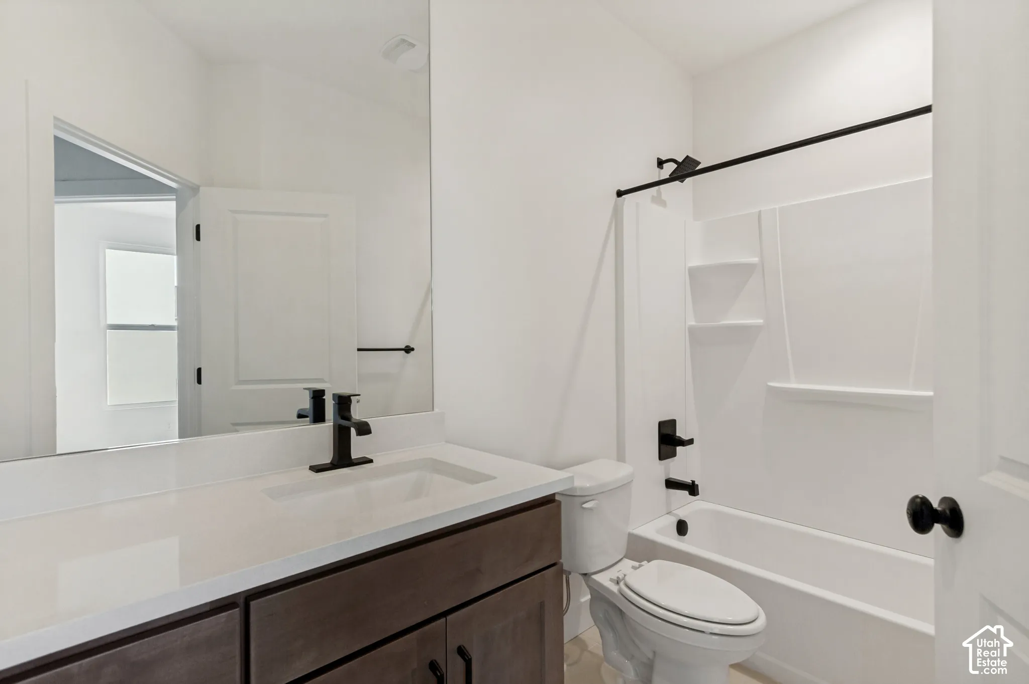 White bathroom featuring a single vanity with dark wood-finish cabinetry, white countertop, and integrated sink