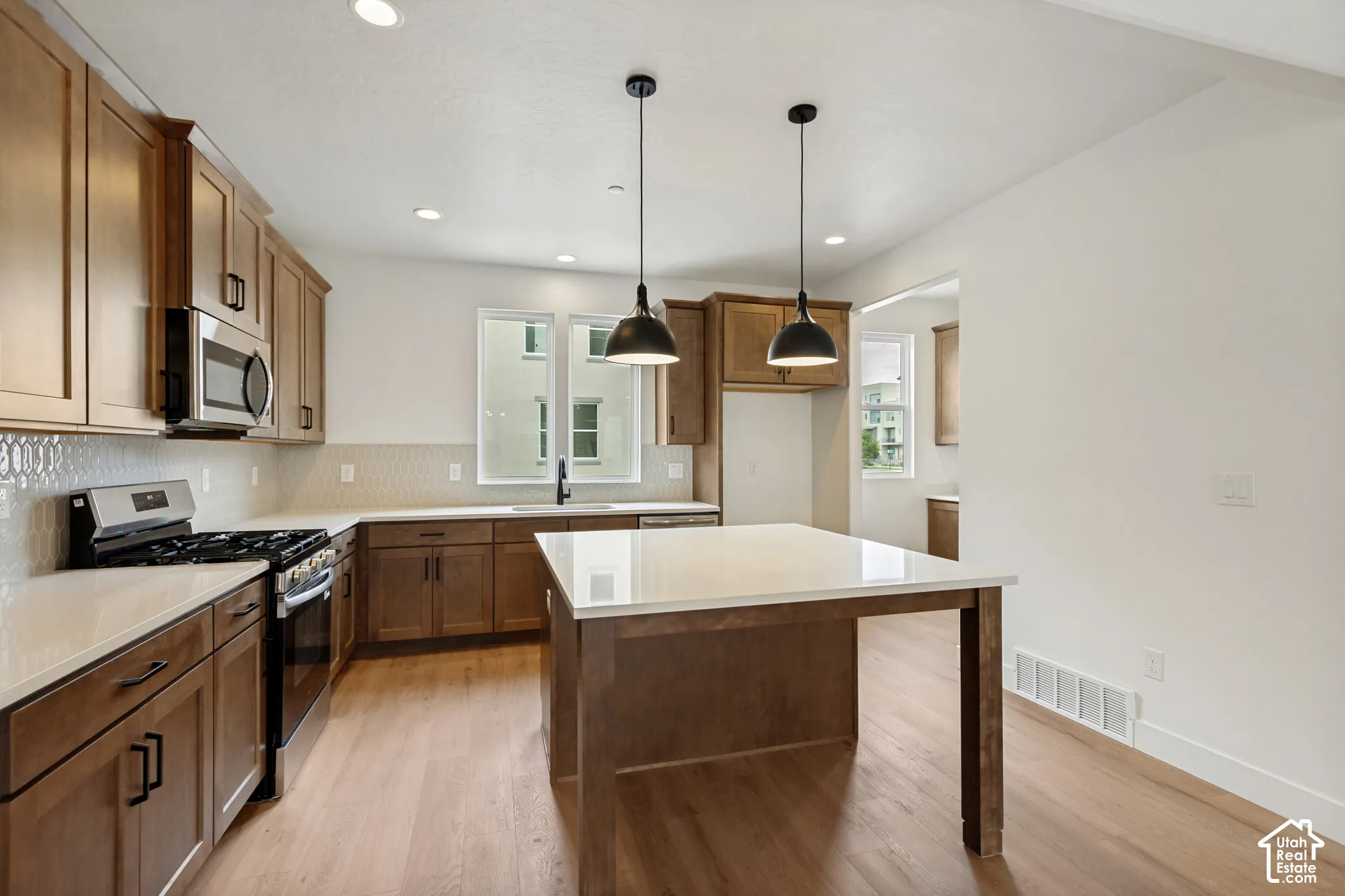 Wood-finish flooring, recessed lighting, and a kitchen island with pendant lighting