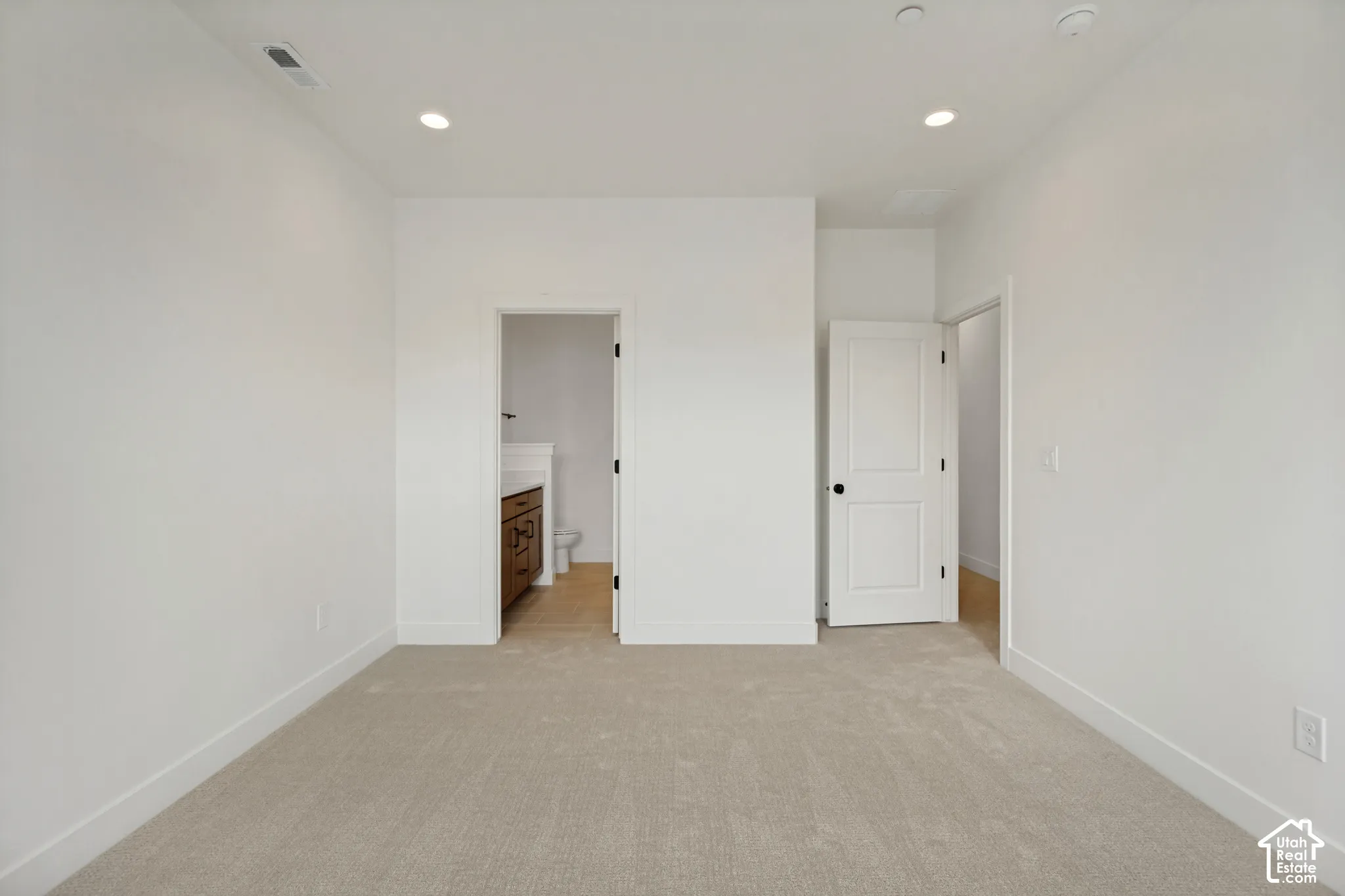 Plush carpeting, recessed lighting, and white interior doors with black hardware