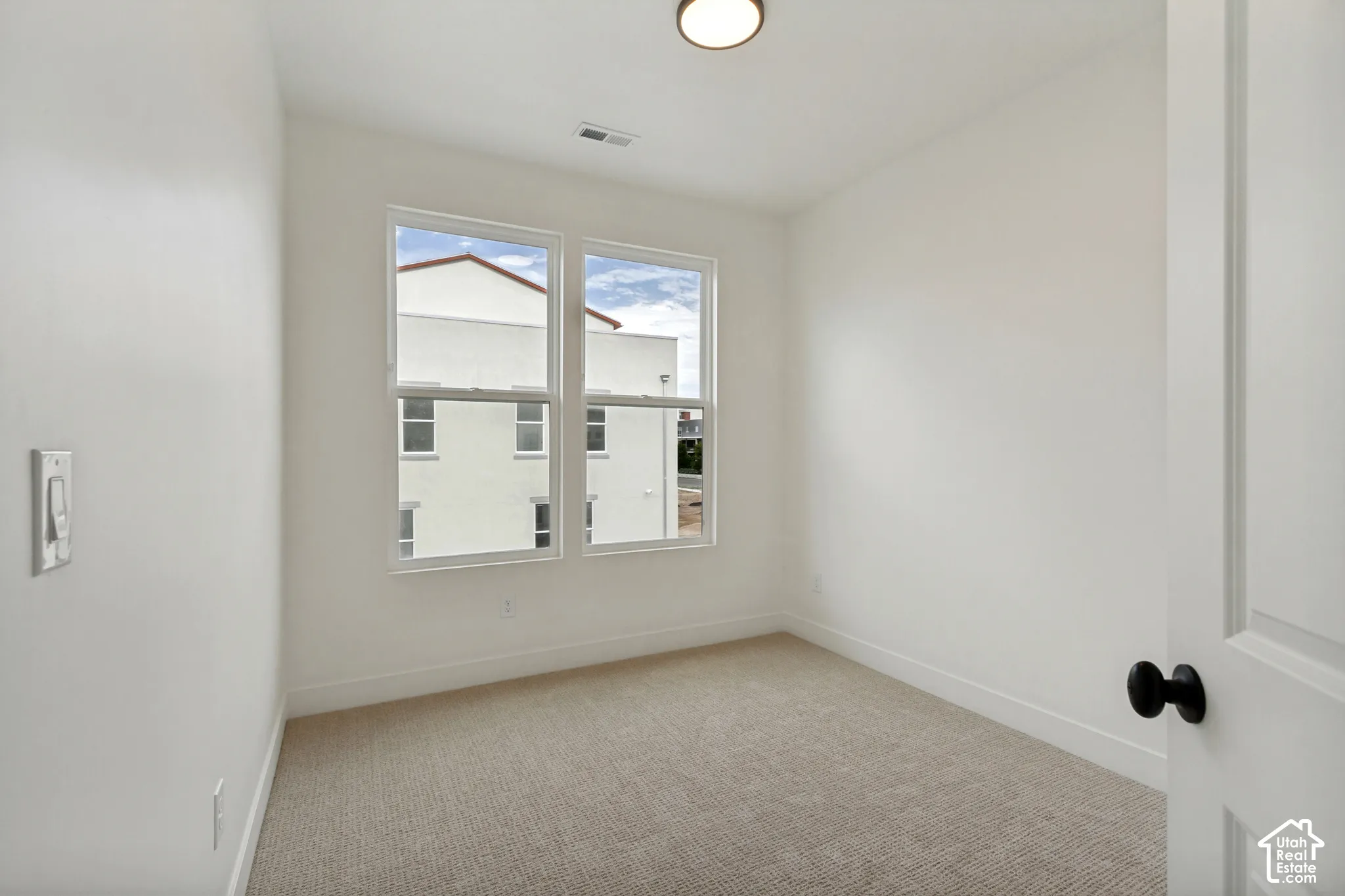 Recessed lighting, wall-to-wall carpeting, and a two-panel interior door with a matte black knob