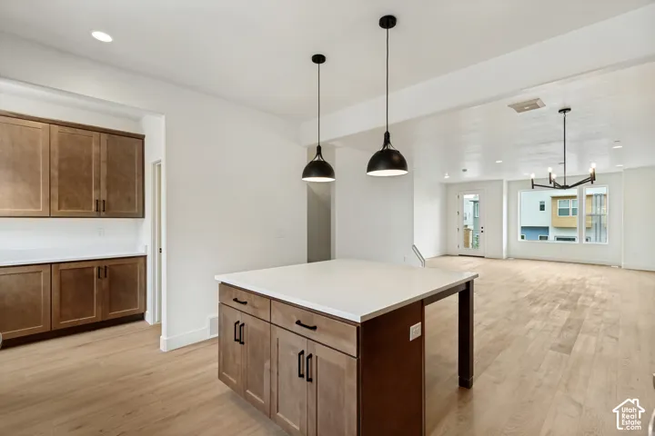 Expansive open-concept living area featuring light wood-finish flooring, a kitchen island with white countertop, and dark cabinetry