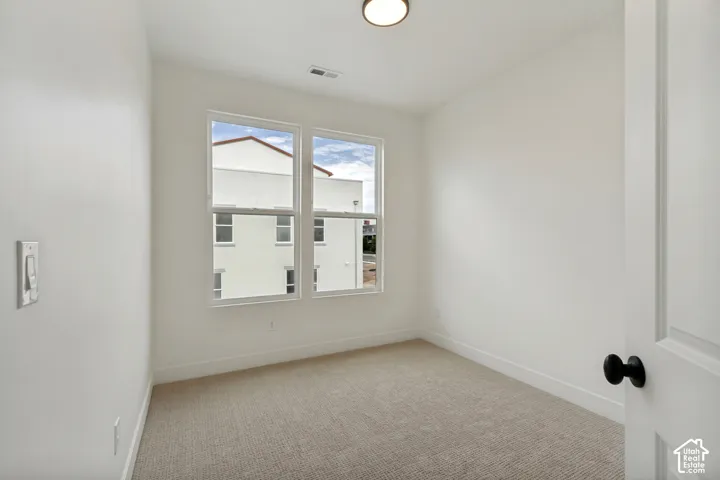 Recessed lighting, wall-to-wall carpeting, and a two-panel interior door with a matte black knob