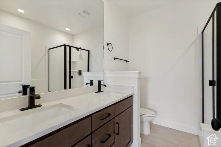 Dual vanity with matte black fixtures, integrated sinks, white countertop, dark wood-finish cabinetry, and a glass-enclosed shower with black framing