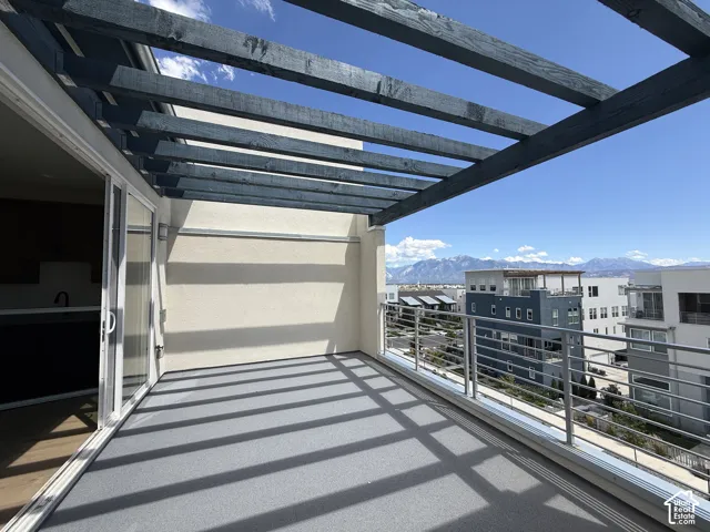 Expansive outdoor patio with a slatted pergola, grey outdoor carpeting, and sliding glass door access