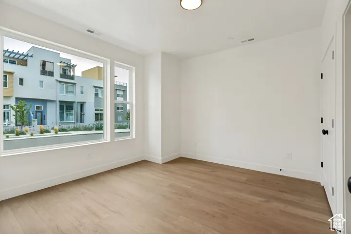 Recessed ceiling light, white painted walls, light wood-finish flooring, white trim, and a white paneled door with dark hardware