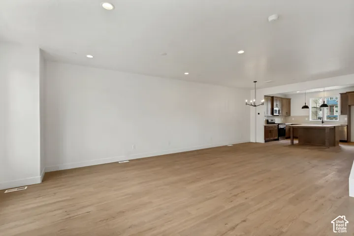 Open-concept living area with wood-finish flooring, recessed lighting, and a modern chandelier