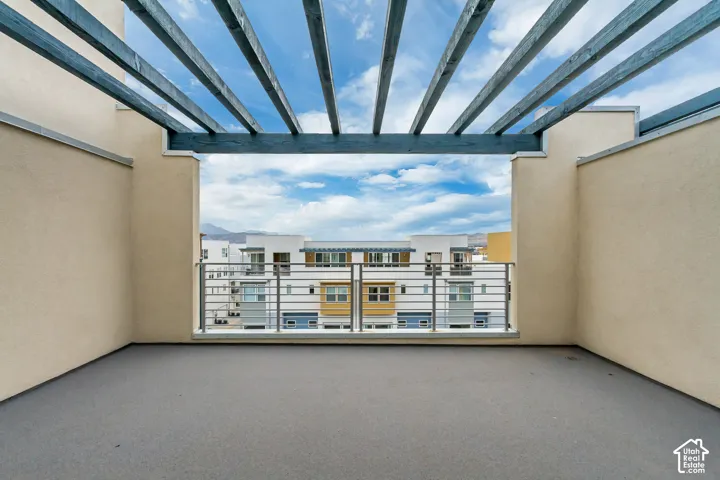Rooftop deck featuring a slatted pergola, stucco walls, and a metal railing