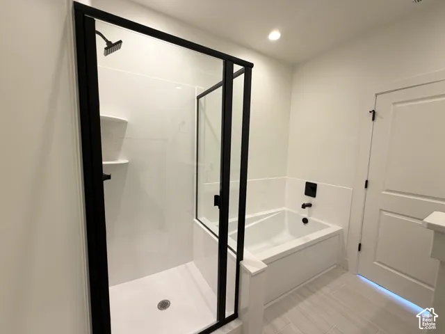 Shower enclosure with matte black framing, integrated shelving, and a built-in bathtub with matte black fixtures