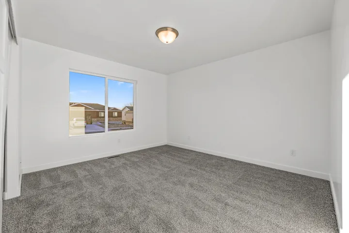 Neutral wall paint, gray carpet flooring, flush mount lighting, and a large window