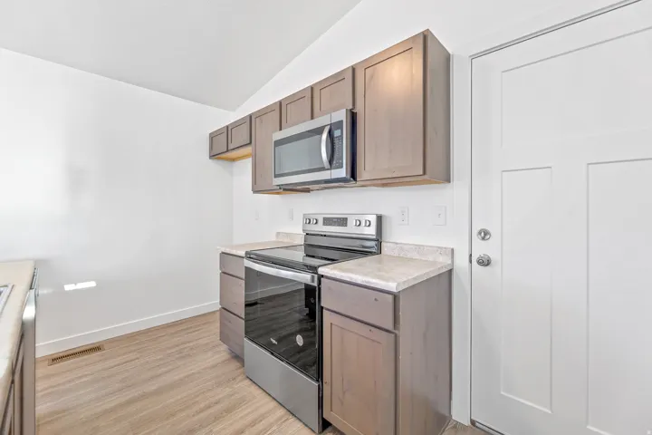 Kitchen featuring wood-finish cabinetry, light-toned countertops, and stainless steel appliances