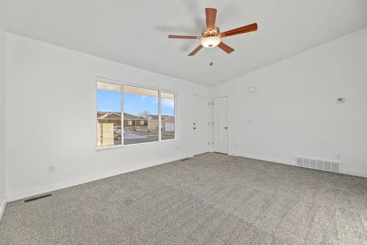 Expansive room featuring light gray carpeting and white walls