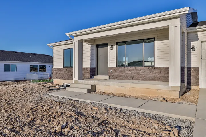 Covered entry with concrete steps and landing, featuring dark stacked stone siding and light horizontal siding