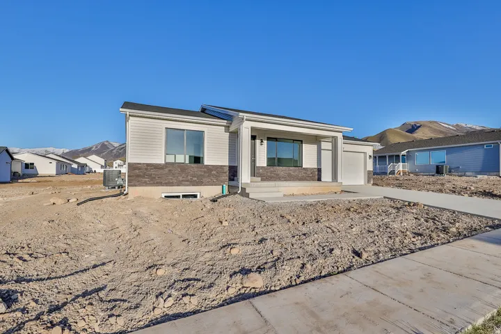 Contemporary exterior with light-colored siding, dark stone accent details, and a covered entry