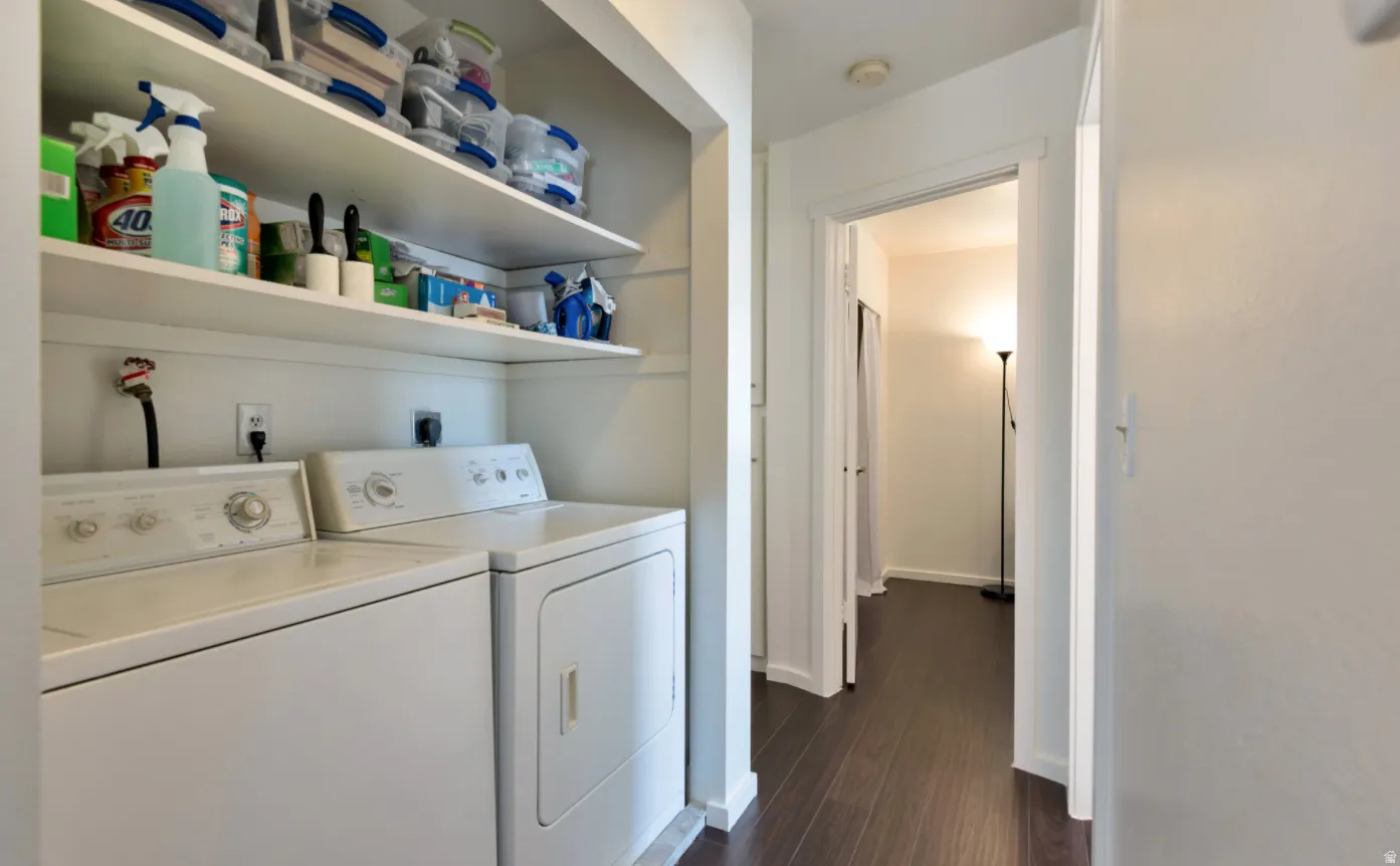 Laundry area featuring a side-by-side washer and dryer, open shelving, and wood-finish flooring