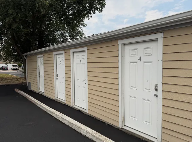 Tan horizontal siding exterior with multiple white panel doors